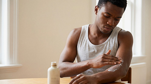 African American man putting lotion on his eczema