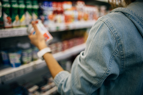 woman with rosacea checking the ingredients on a skin care product package 